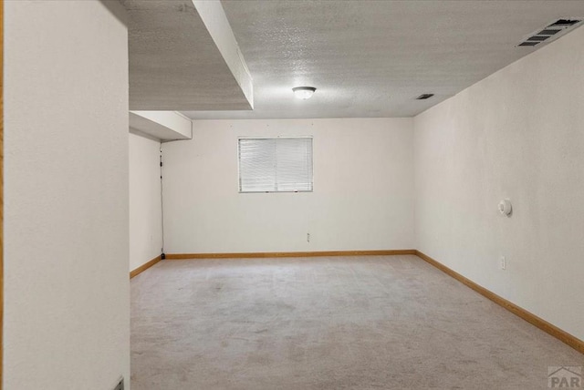 unfurnished room with baseboards, visible vents, a textured ceiling, and light colored carpet