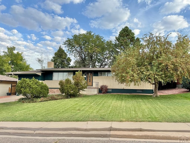 view of front of home with brick siding, a chimney, and a front lawn