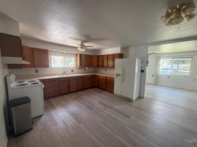 304 S Mullen, Lamar, CO 81052 - kitchen with white appliances, a textured ceiling, under cabinet range hood, a ceiling fan, and plenty of natural light