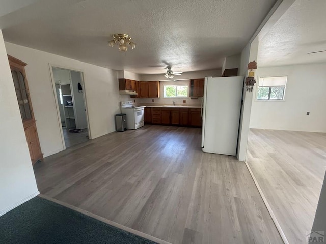 304 S Mullen, Lamar, CO 81052 - kitchen featuring white appliances, ceiling fan, light wood-type flooring, healthy amount of natural light, and a textured ceiling