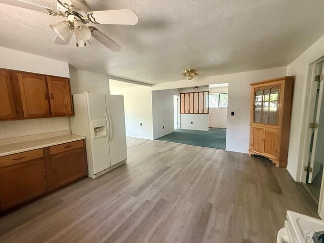 304 S Mullen, Lamar, CO 81052 - kitchen with white fridge with ice dispenser, brown cabinets, a textured ceiling, light wood-style flooring, and ceiling fan