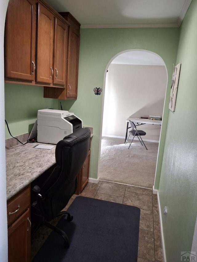 home office featuring arched walkways, built in study area, crown molding, and baseboards