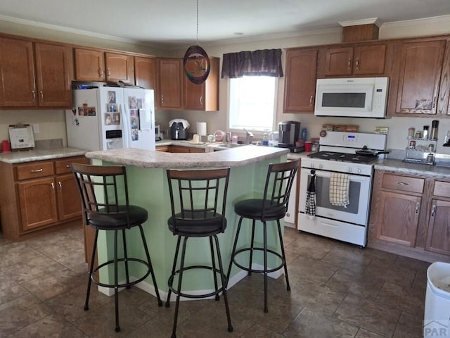 kitchen featuring white appliances, a breakfast bar, a kitchen island, light countertops, and decorative light fixtures