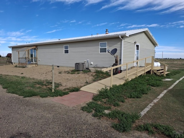 back of property featuring central air condition unit and metal roof