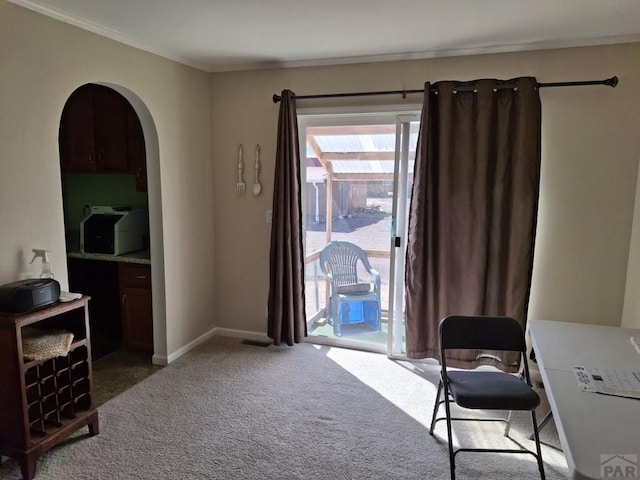 living area featuring carpet floors, baseboards, arched walkways, and ornamental molding