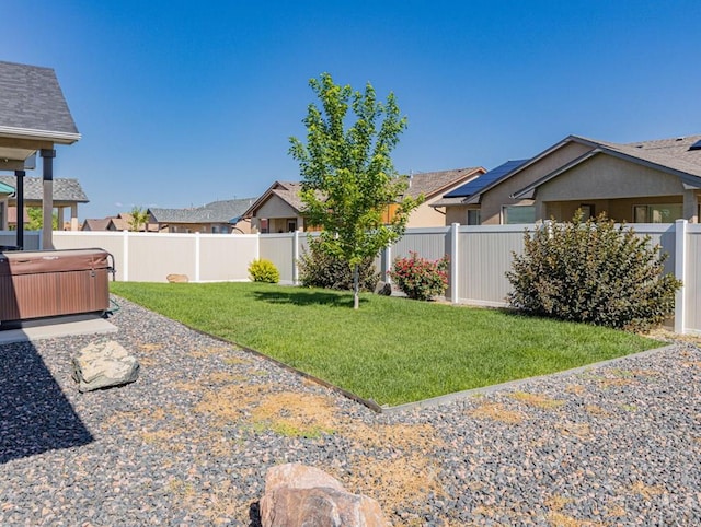 view of yard with a residential view, a fenced backyard, and a hot tub