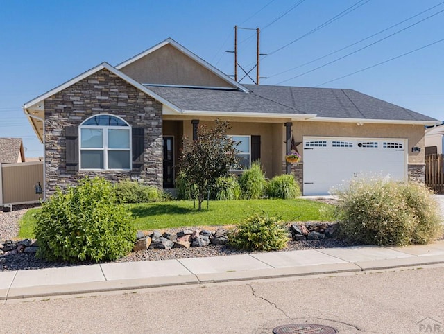 view of front facade with an attached garage, a front yard, fence, and stucco siding