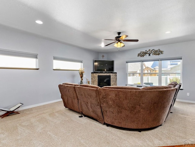 living area featuring recessed lighting, light carpet, a ceiling fan, baseboards, and a glass covered fireplace