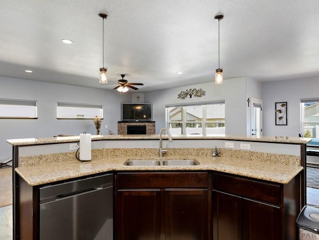 kitchen with pendant lighting, stainless steel dishwasher, open floor plan, dark brown cabinetry, and a sink