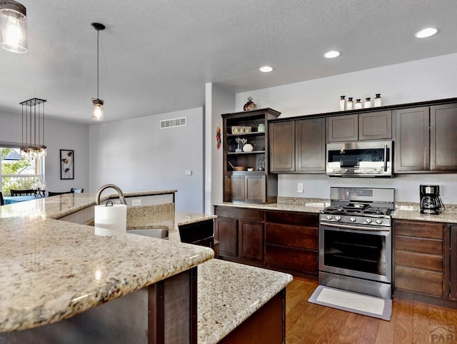 kitchen with visible vents, hanging light fixtures, appliances with stainless steel finishes, dark brown cabinetry, and a sink