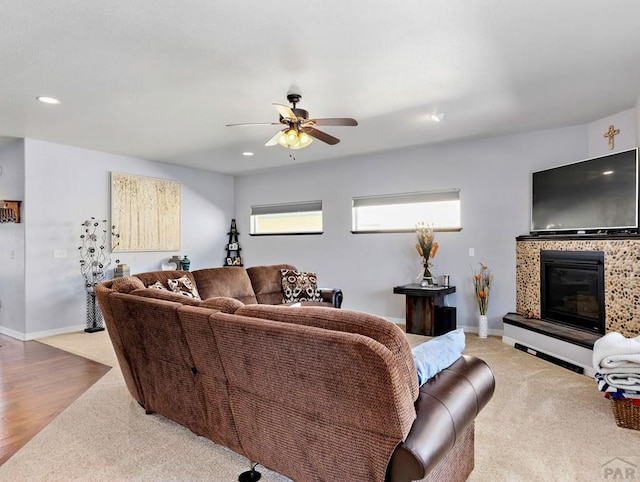 living area featuring baseboards, a glass covered fireplace, and recessed lighting