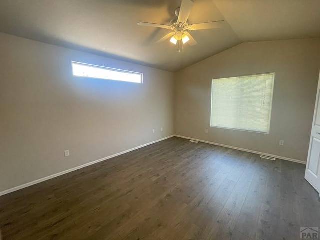 spare room featuring vaulted ceiling, dark wood finished floors, baseboards, and ceiling fan