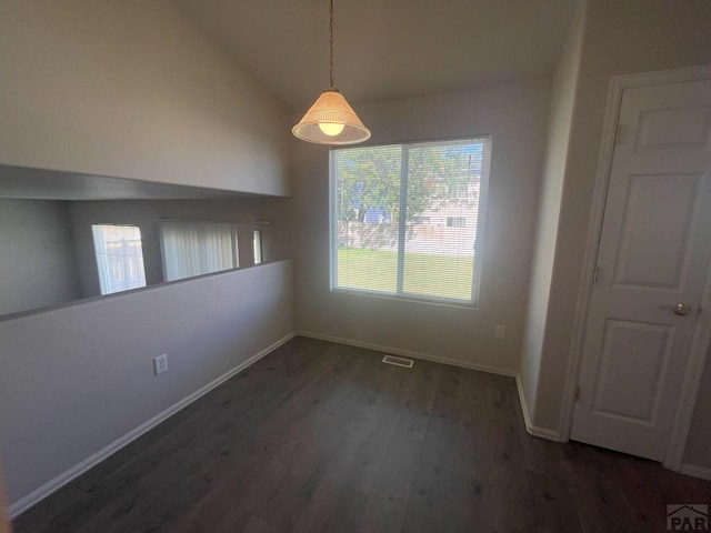 unfurnished dining area featuring lofted ceiling, dark wood-style flooring, visible vents, and baseboards