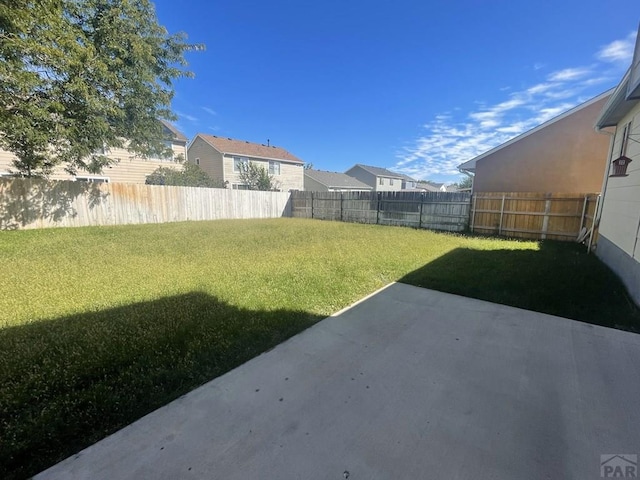 view of yard featuring a patio area, a fenced backyard, and a residential view