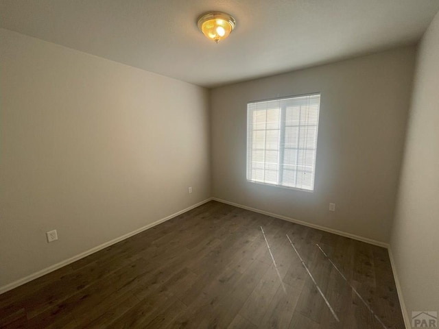 empty room featuring dark wood-style flooring and baseboards