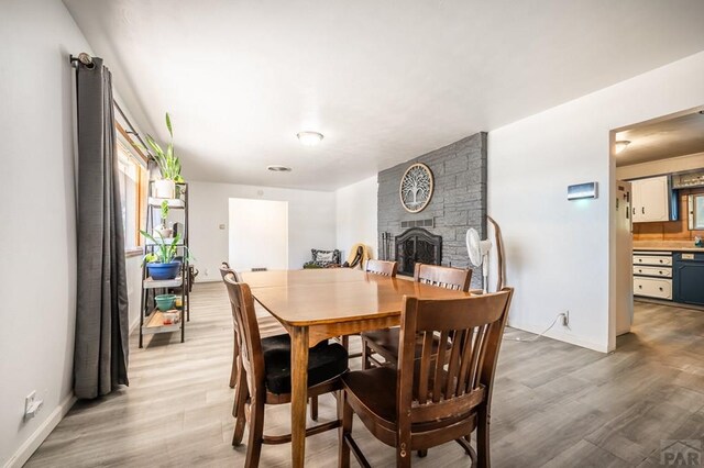 dining area with a large fireplace, wood finished floors, and baseboards