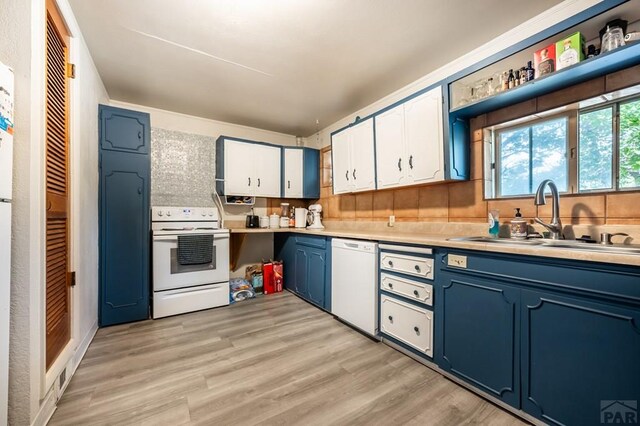 kitchen with white appliances, blue cabinets, light countertops, white cabinetry, and a sink