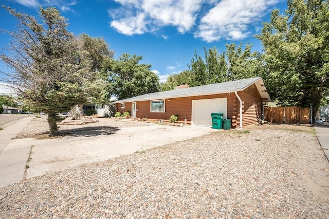 view of front of house featuring log exterior, driveway, a chimney, and an attached garage