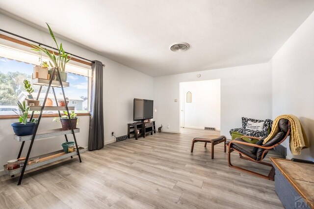 sitting room with light wood-type flooring, visible vents, and baseboards