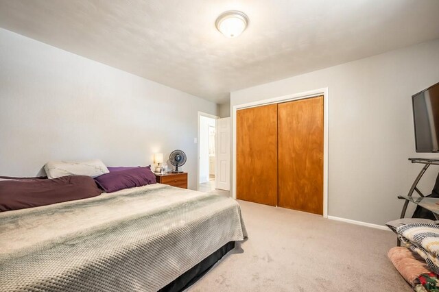 carpeted bedroom with a closet and baseboards