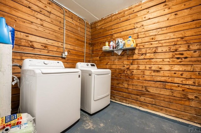 clothes washing area with laundry area, wood walls, and independent washer and dryer