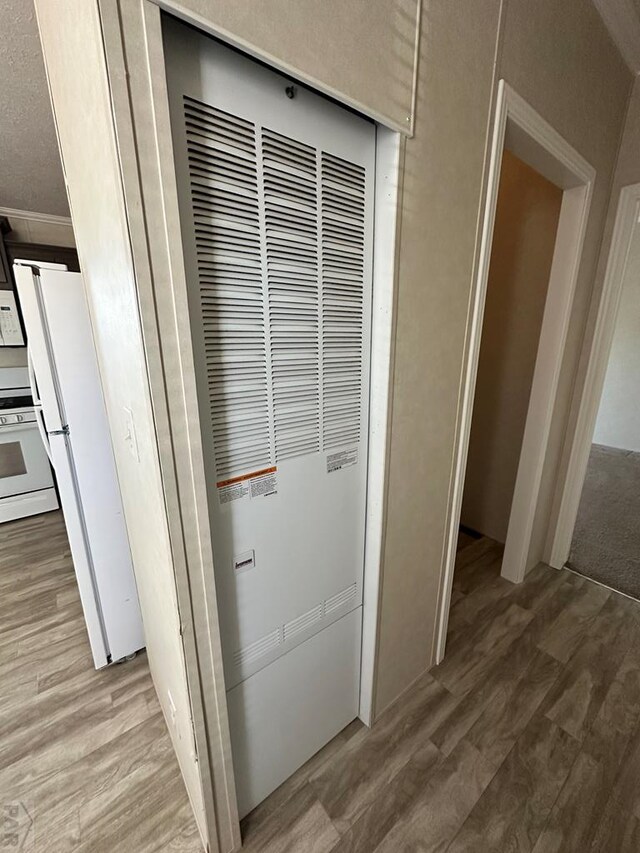 details featuring white appliances, a heating unit, and wood finished floors