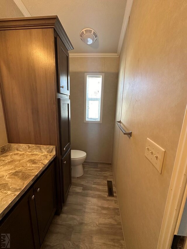 bathroom with visible vents, toilet, wood finished floors, crown molding, and vanity