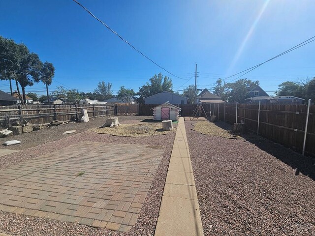 view of yard featuring a patio area, a fenced backyard, a storage unit, and an outdoor structure