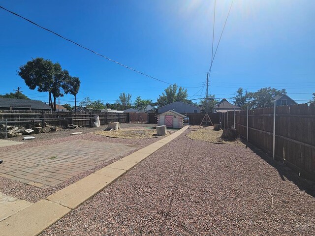 view of yard featuring a patio area, a fenced backyard, an outdoor structure, and a storage shed