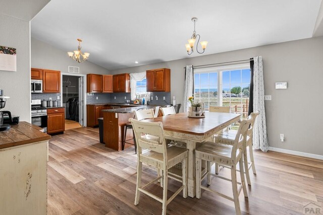 dining room featuring light wood finished floors, visible vents, vaulted ceiling, and a notable chandelier