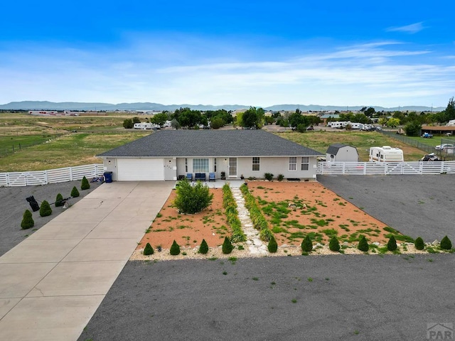 ranch-style house featuring a garage, driveway, fence, and a mountain view