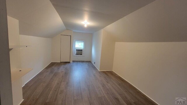 additional living space featuring lofted ceiling, dark wood-style flooring, and cooling unit