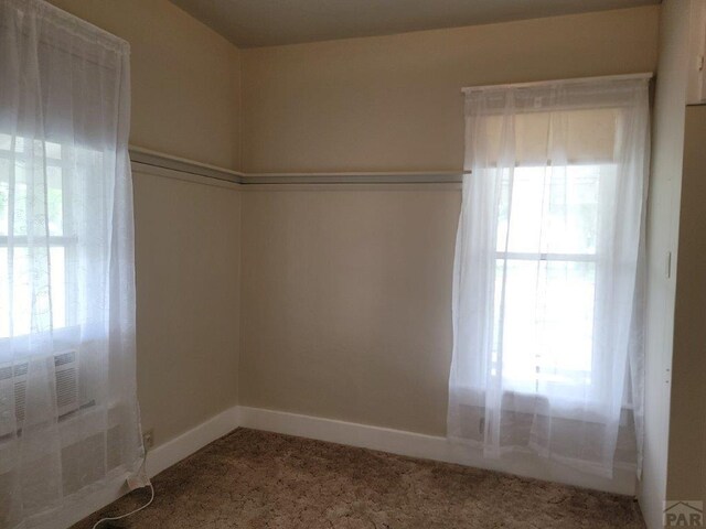 unfurnished room featuring carpet and baseboards