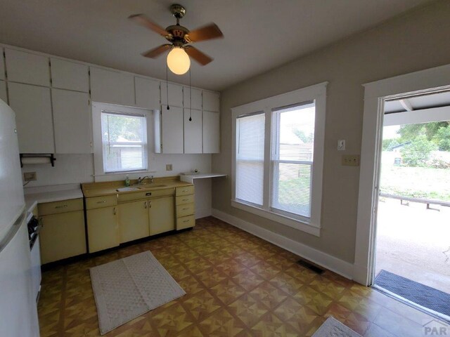 kitchen featuring light countertops, light floors, a sink, and white cabinetry