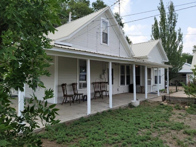 rear view of property featuring covered porch, metal roof, and a yard