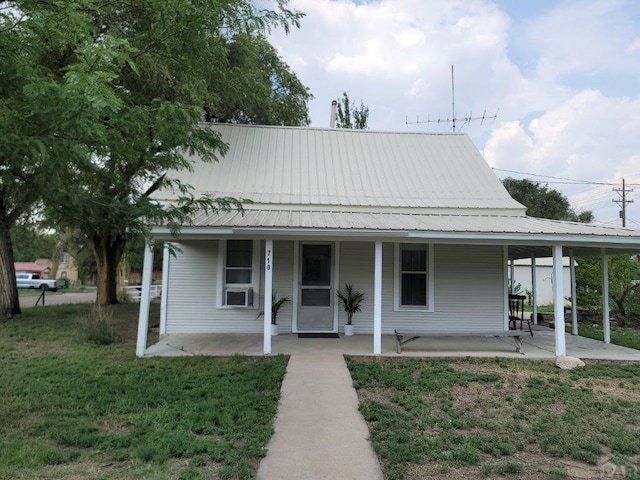 farmhouse-style home with a porch, metal roof, and a front yard