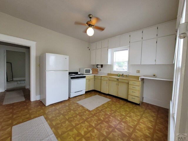 kitchen with white appliances, white cabinetry, light floors, and a sink