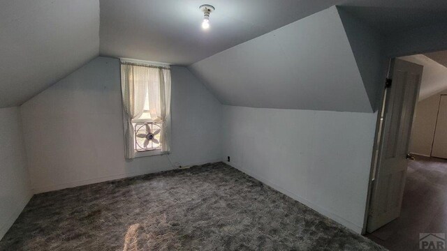 additional living space featuring vaulted ceiling and dark carpet