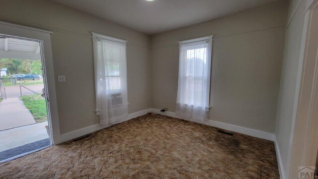 carpeted empty room featuring baseboards