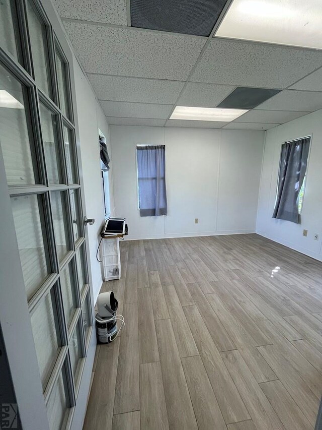 spare room featuring light wood-type flooring and a paneled ceiling