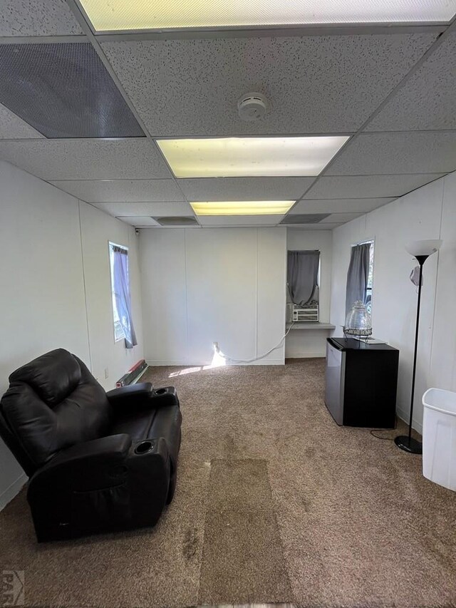 basement featuring carpet floors, stainless steel fridge, and a drop ceiling