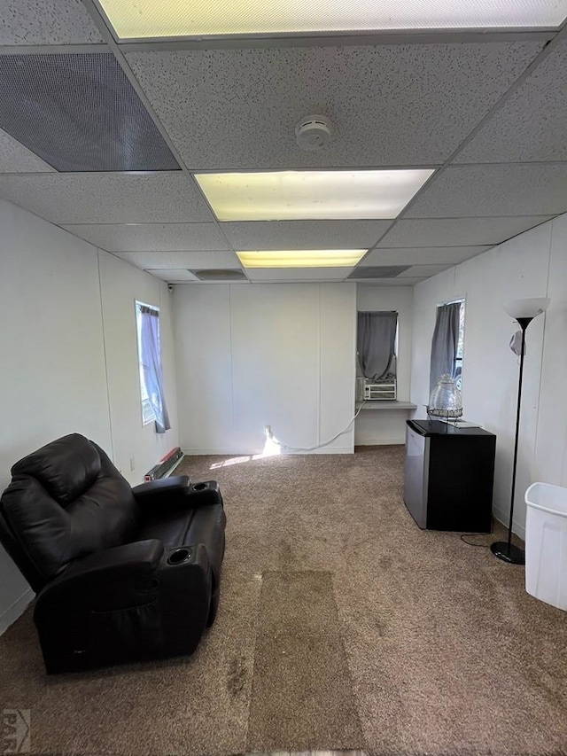 basement featuring carpet floors, stainless steel fridge, and a drop ceiling