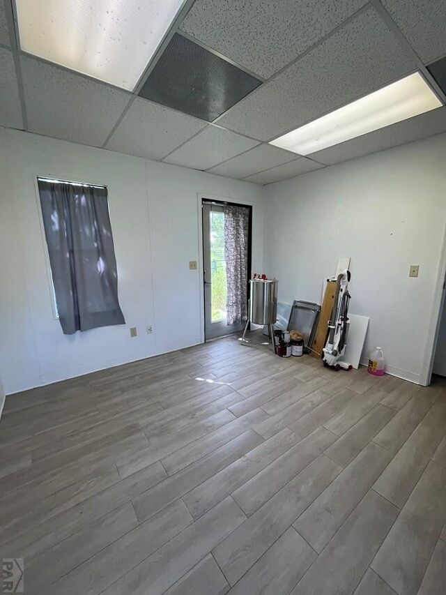 basement with a drop ceiling and wood finished floors