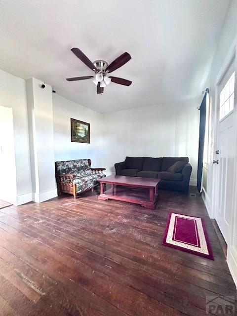 living area featuring a ceiling fan, dark wood-style flooring, and baseboards