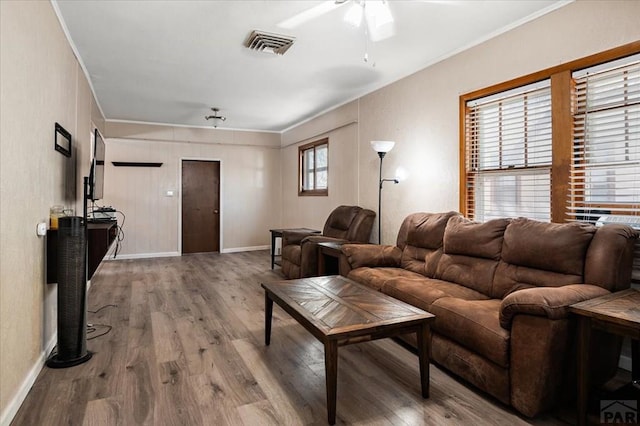 living room featuring crown molding, baseboards, and wood finished floors