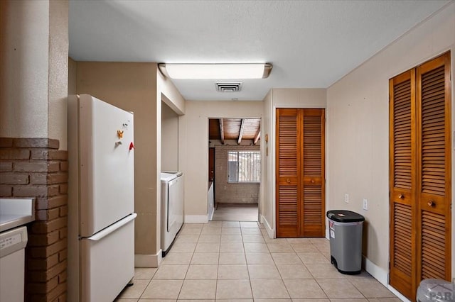 kitchen with washer / dryer, baseboards, light tile patterned floors, and white appliances
