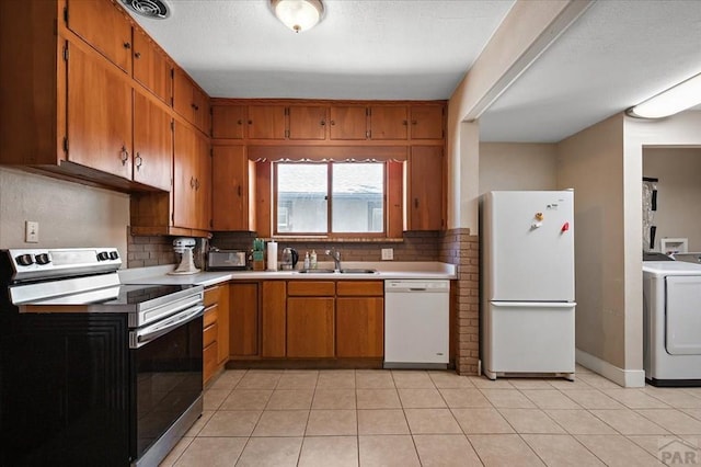 kitchen with decorative backsplash, washer / dryer, white appliances, light countertops, and a sink