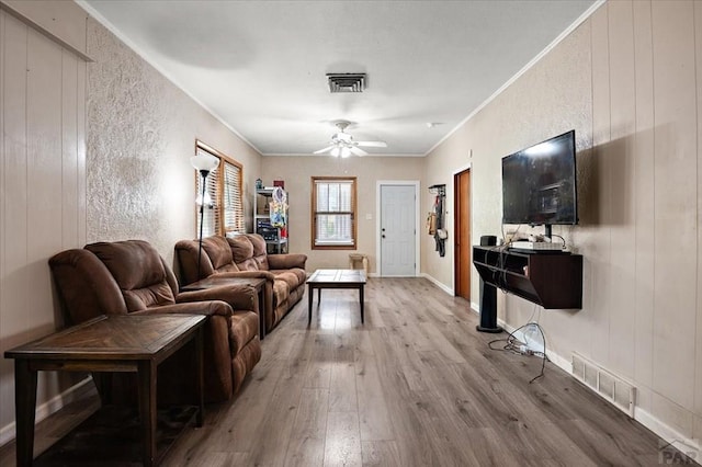living room featuring visible vents, a ceiling fan, crown molding, and wood finished floors
