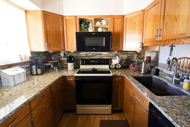 kitchen featuring brown cabinets, a sink, light stone countertops, black appliances, and backsplash