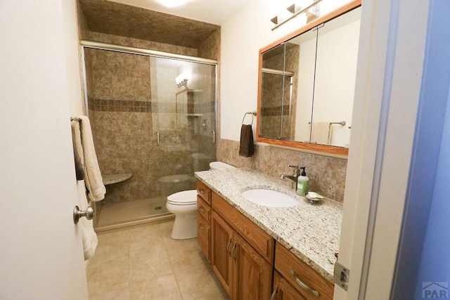 full bathroom featuring a stall shower, decorative backsplash, toilet, tile patterned floors, and vanity